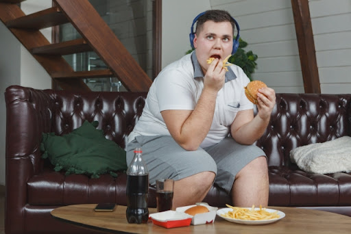 ジャンクフードを食べる太った男性